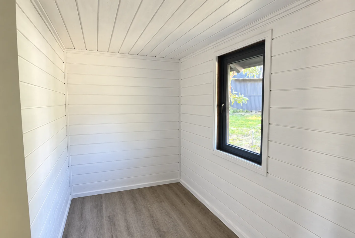 Dormitorio con muros blancos y ventana hacia el jardín