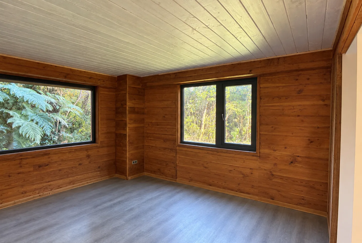 Dormitorio amplio con ventanales en dos muros hacia el bosque