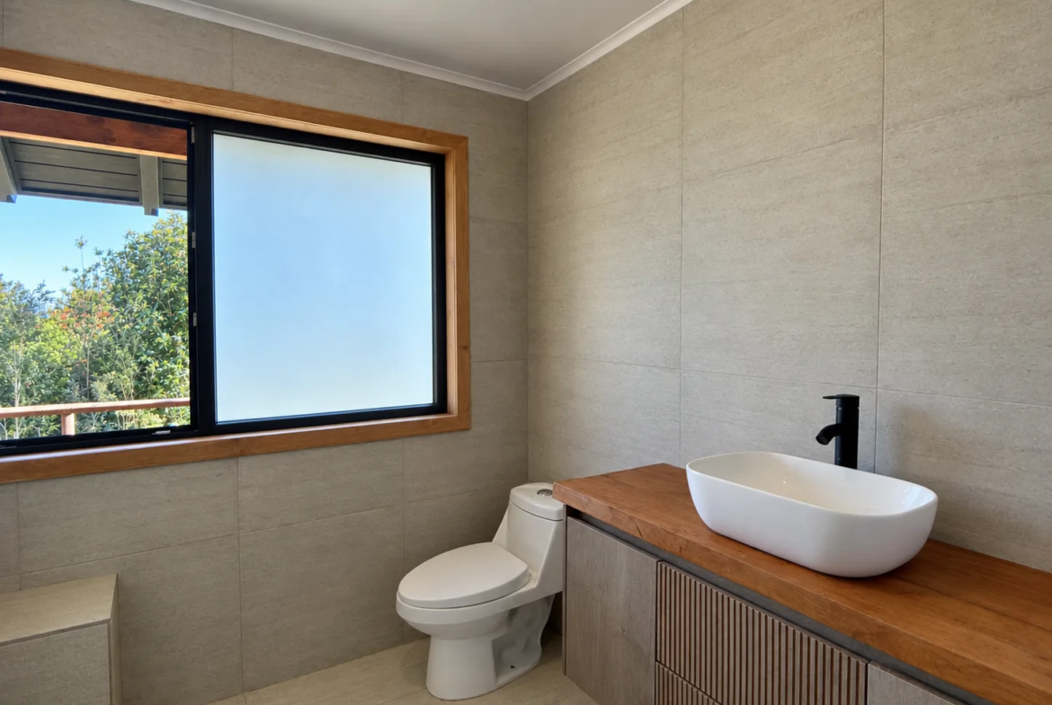 Baño con lavamanos sobre cubierta de madera y ventana al jardín