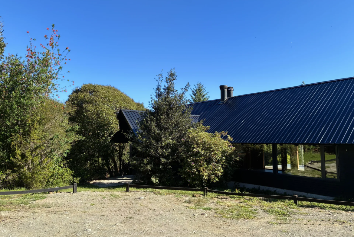 Vista exterior de la casa entre árboles nativos