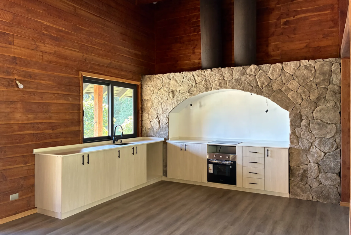 Cocina integrada al living comedor, con muro de piedra