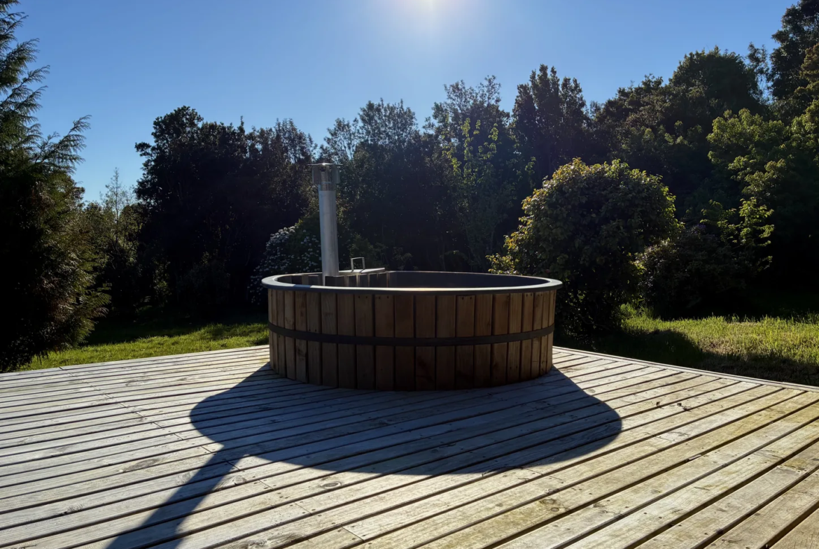Tinaja de madera sobre terraza deck con bosque nativo de fondo