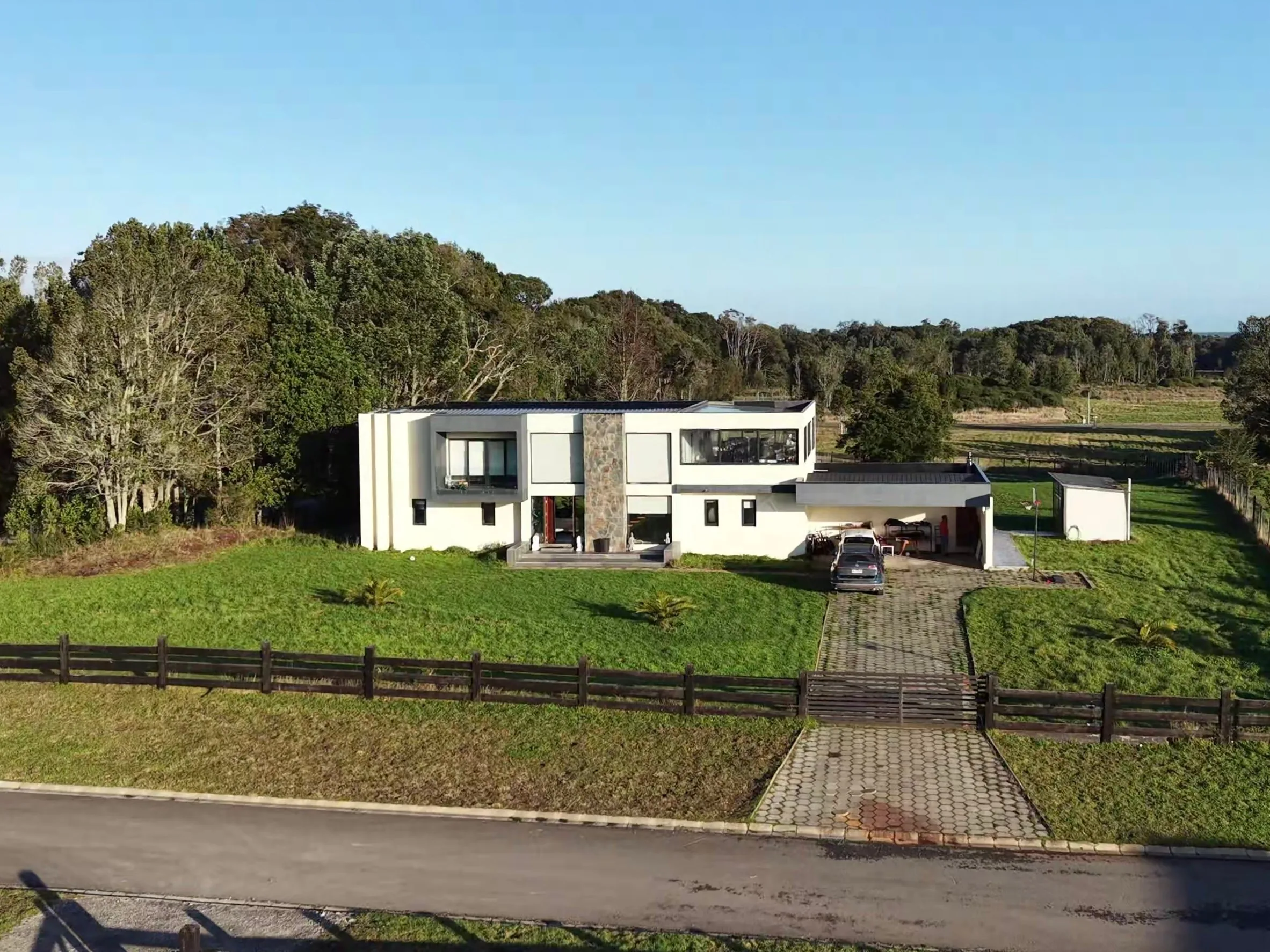 Casa de dos pisos rodeada de bosque nativo, con camino de acceso empedrado y jardín Casa de dos pisos rodeada de bosque nativo, con camino de acceso empedrado y jardín