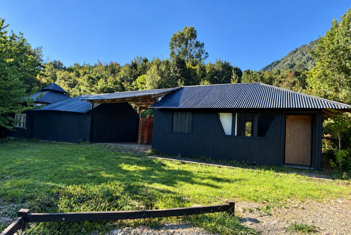 Bodega y construcciones anexas de madera, rodeadas de bosque nativo